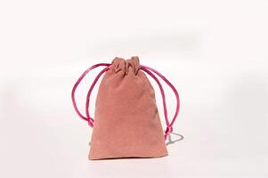 Pink velvet drawstring pouch with bright strings on white background photo