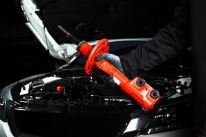 Car Shock Absorber, Mechanic holding a red shock absorber strut for a car with the vehicle's open hood and engine visible in the background. photo