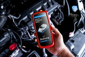 Vehicle Diagnostics Wireless Tool, A handheld device OBD2 scanner diagnostic for car repair by technician in auto service garage. photo