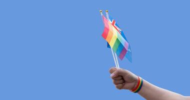 Rainbow flags and Australian flag showing in hands against clear bluesky, copy space, concept for calling people to support and respcet the genger diversity and celebrate lgbtq in pride month. photo
