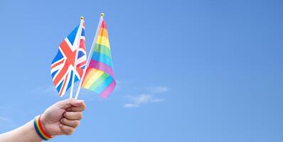 Rainbow flags and England flag showing in hands against clear bluesky, copy space, concept for calling people to support and respcet the genger diversity and celebrate lgbtq in pride month. photo