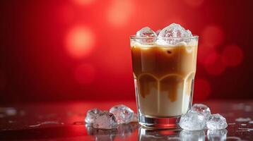 A glass of iced coffee with frothy milk and ice cubes, set against a vibrant red background. photo
