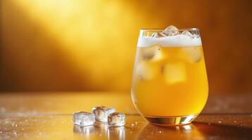 A refreshing beverage in a glass with ice cubes on a golden background. photo
