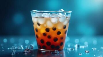 A glass filled with a refreshing beverage, containing ice and Boba pearls, rests upon a table, with a blurred background. photo