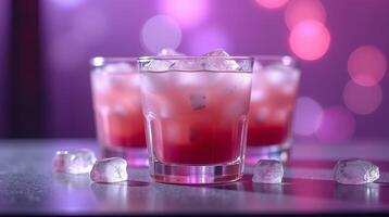 Three glasses of red beverage with ice, on a table against a blurred background. photo