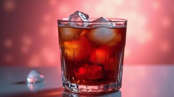 A glass of dark liquid with ice cubes against a red background. photo