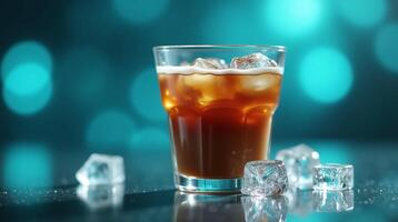A glass of iced coffee with frothy foam rests on a reflective surface, surrounded by scattered ice cubes against a blurred bokeh backdrop. photo