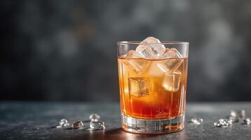 Amber beverage with ice, set against a blurred, dark background. photo