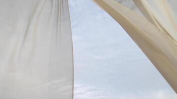 Semi-transparent breezy sheer flowing curtain blowing in the wind with cloudy sky behind it video