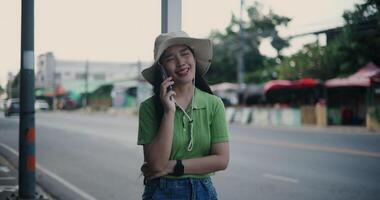 Handheld shot, Cheerful young woman happily talks on the phone while standing on a sidewalk in the city. video