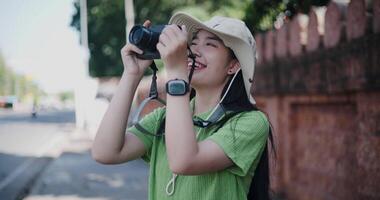 Handheld selective focus shot, Happy young Asian woman standing enjoying the surrounding view while taking photos with her camera. video