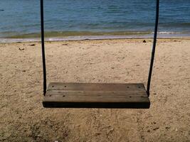 Wooden swing with and and blue sea background, suitable for product such as health, lifestyle, relaxation, fresh drinks, frozen desserts, and leisure photo
