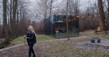 A woman explores a forest with a glass house, blending nature and tech video