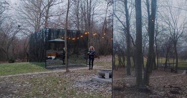 A woman explores a serene forest with a stunning glass house video
