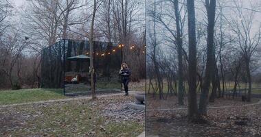 A man and woman showcase harmony in a glass house in the woods video