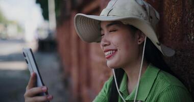 Handheld selective focus shot, Relaxed young woman sits against a brick wall and happily chats with someone on mobile phone. video