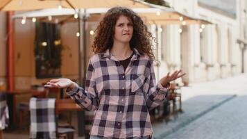 Surprised frustrated young woman raising hands asking reason of failure demonstrating disbelief video