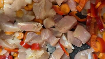 Raw chicken pieces with sliced bell peppers and onions create a colorful culinary backdrop, ideal for cooking or recipe concepts video