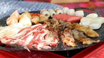 white rectangular plate containing various types of processed fish cakes and sausages, which are commonly used in hot cooking on a checkered cloth background. photo