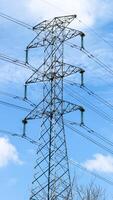 This is tall transmission line tower on clear blue sky background, photo