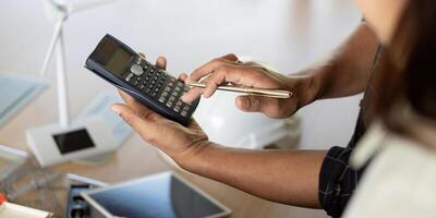 Sustainability and Engineering. Engineer using calculator for sustainable project analysis. photo