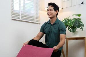 Wellness and Couple Connection. A man smiling while holding a yoga mat in a bright, inviting space. photo