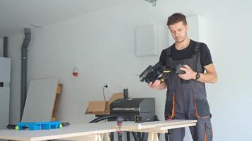 Worker in workwear attaching vacuum hose to electric jigsaw for woodworking on workbench in home workshop video
