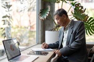 Elderly man analyzing data on tablet in modern workspace photo