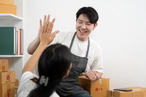 Couple collaborating in a business setup, sharing joyful moments while handling packages. photo