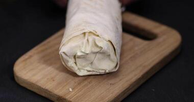 one shawarma made from thin wheat tortilla with meat with tomatoes and sauce, fast food made from various ingredients packed in foil photo
