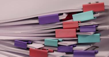 white sheets of paper are connected by multicolored metal clips, stacked sheets of paper for documents are joined together, sheets of paper is different in each clip photo