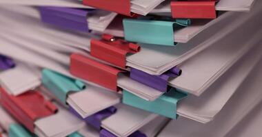 sheets of paper are connected by multicolored metal clips, stacked sheets of paper for documents are joined together, sheets of paper is different in each clip photo