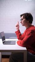 A man in glasses is sitting at a table with a laptop. a man gets a great idea. inspired man at work video