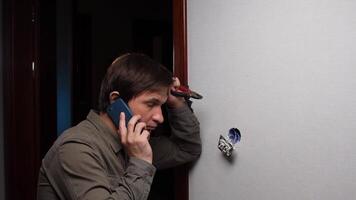 A man talking on a cell phone while standing in front of a wall video