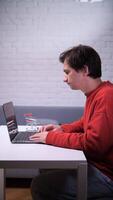 A man sitting at a table with a laptop, online shopping store, adding products to online shopping cart video