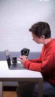 A man sitting at a table with a camera and a laptop video