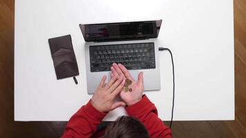A person sitting at a table with a laptop and a coin video