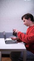 A man sitting at a table with a laptop and a cell phone video