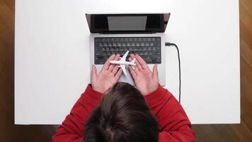 A person using a laptop computer with a remote control video