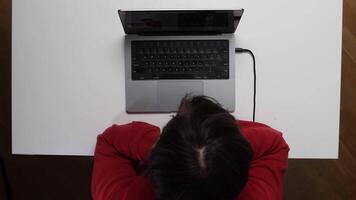 top view Young man covering his face with his hand, overwhelmed by stress and burnout while working remotely at a home office desk, struggling with fatigue and mental health challenges video