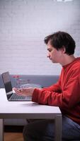 A man sitting at a table with a laptop and a shopping cart video