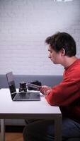 A man sitting at a table with a laptop and a camera video