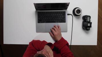 A person sitting at a table with a laptop and a camera video