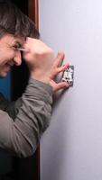 vertical close-up An angry man expresses his anger and negativity on broken electrical wiring, a broken switch. A man hits a screwdriver into the wall, expressing anger, irritation and disappointment video
