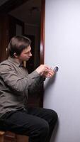 vertical Electrician focused on installing and repairing a light switch on a white wall, using a screwdriver with precision, ensuring safety and proper electrical connections video