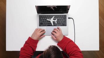 A person typing on a laptop with a plane on it video