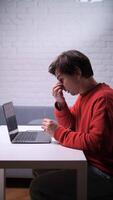 cansado homem esfrega sim sentado às uma mesa com uma computador portátil video