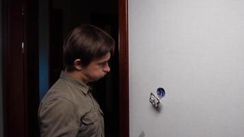 A man is looking at a wall with a small hole video