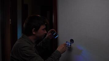 A man is using a flashlight to look at a wall video