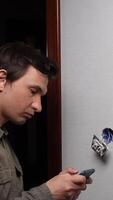 A man looking at his cell phone while standing in front of a wall video